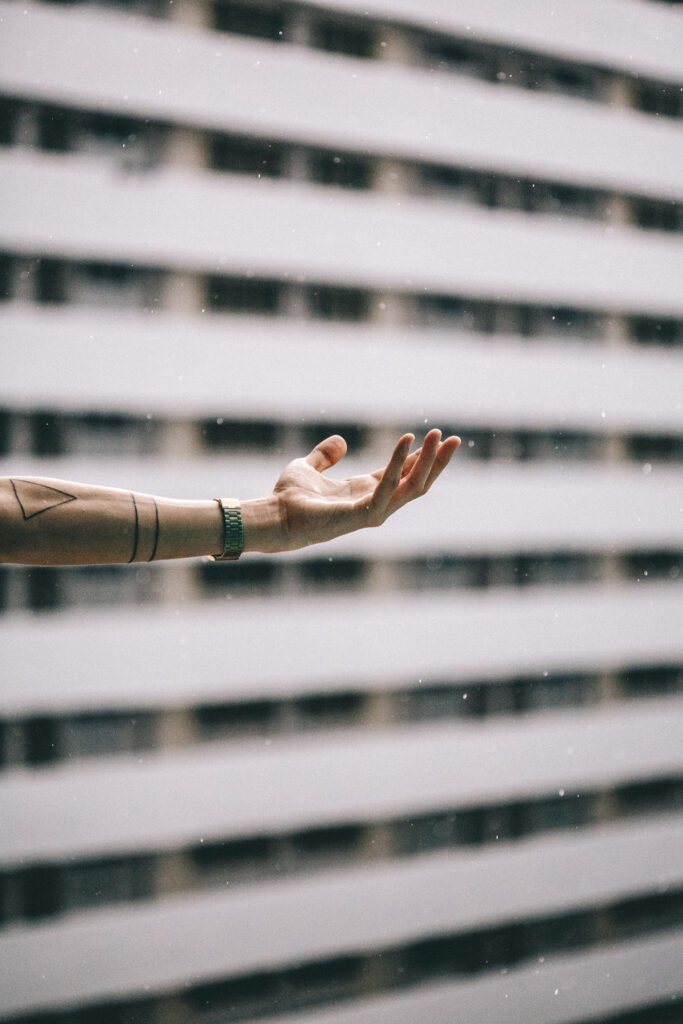 A person 's hand is stretched out in front of a building.