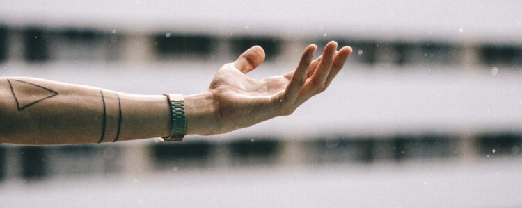A person 's hand is stretched out in front of a building. A person 's hand is stretched out in front of a building.