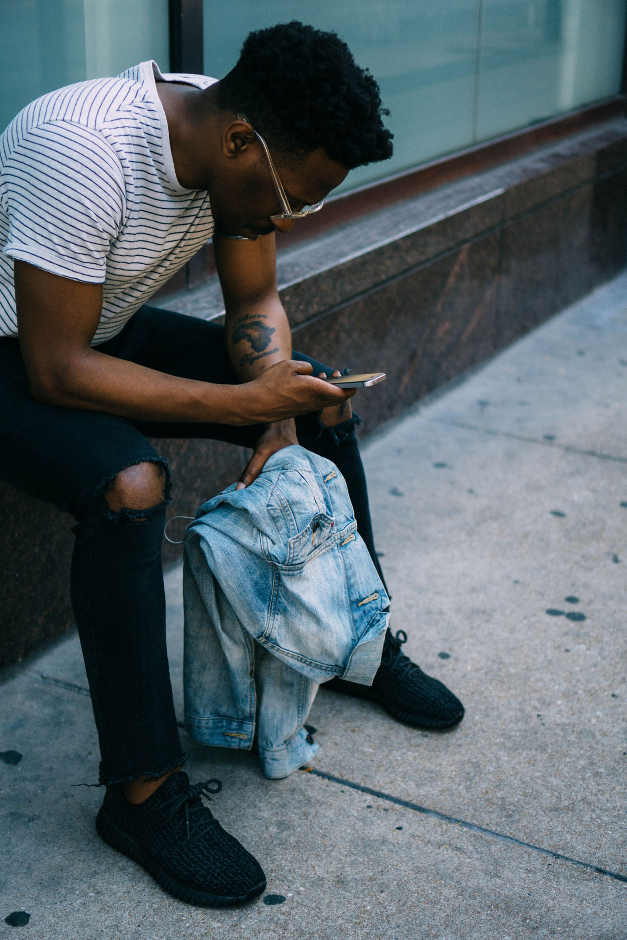 A man sitting on the ground looking at his phone.