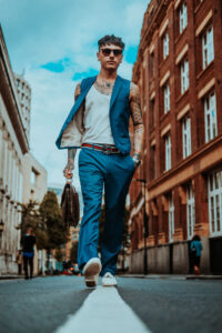 A man in blue pants and vest walking down the street.