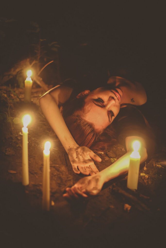 A woman laying on the ground with candles.