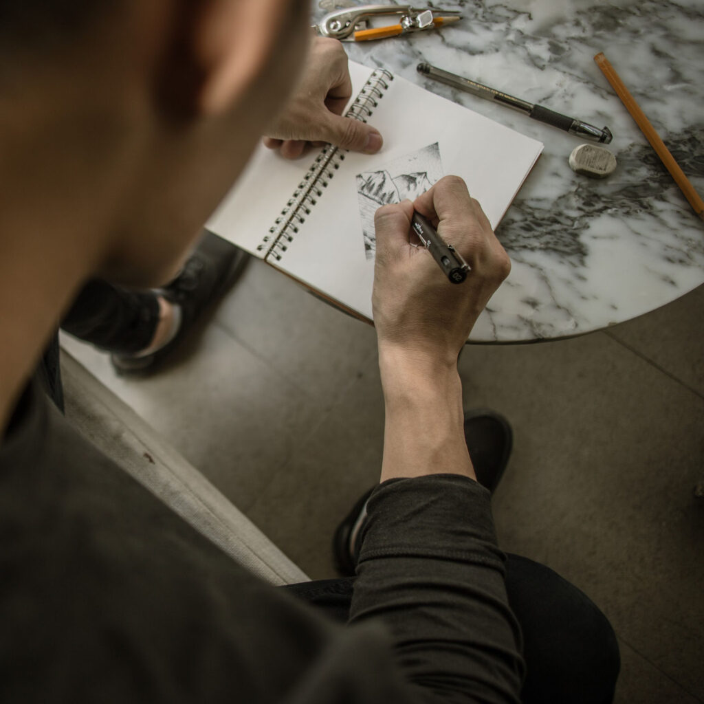 A man drawing on paper with a pencil.