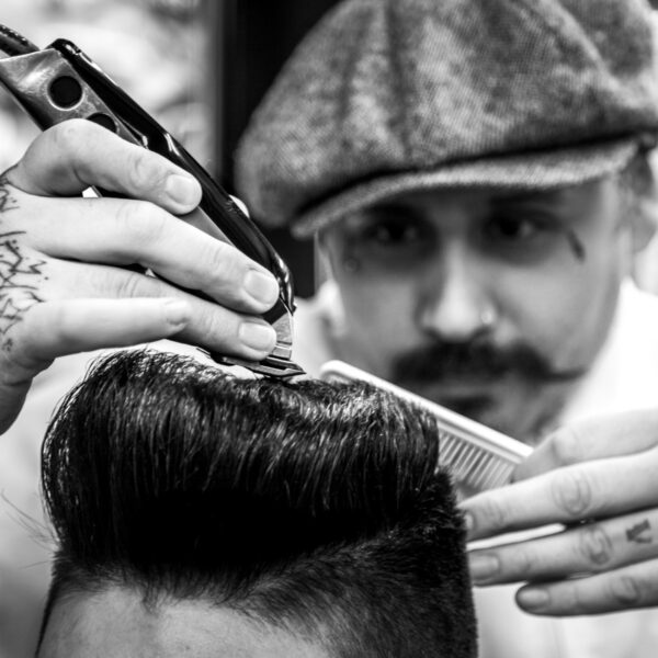 A man getting his hair cut by another man.