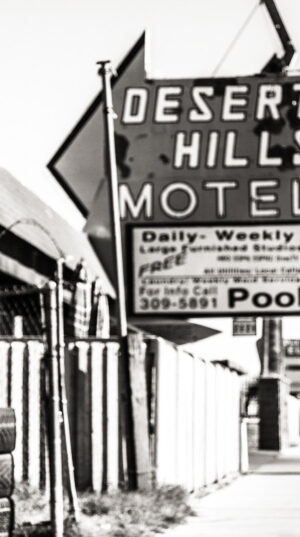 A man standing in front of a motel sign.