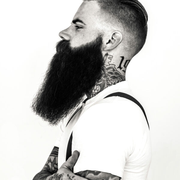 A man with a beard and mustache has a tattoo on his neck.