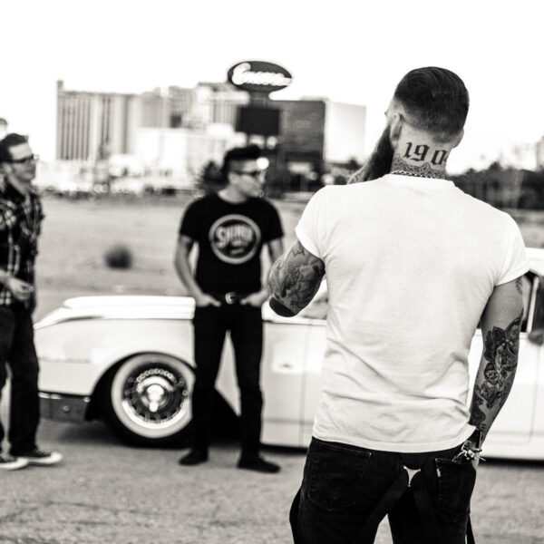 A group of men standing around a car.