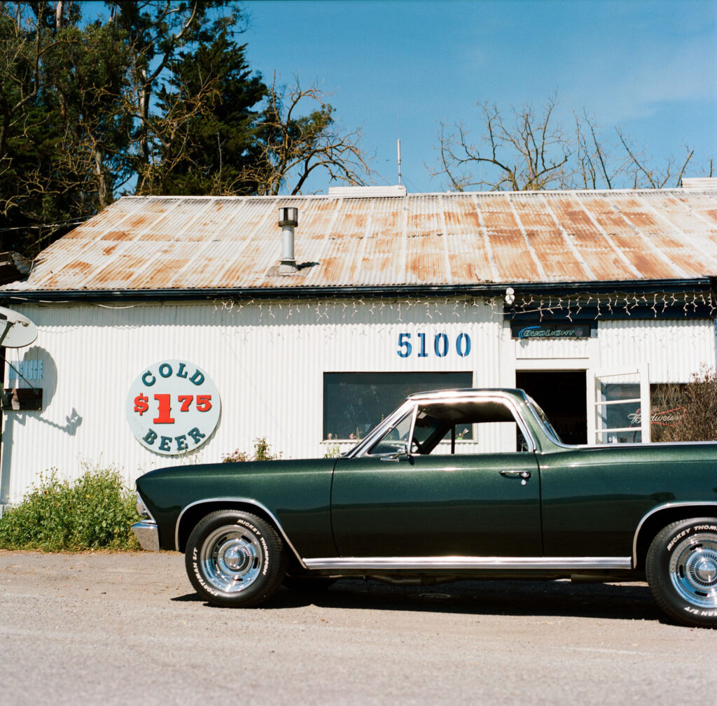 A green car parked in front of an old gas station.